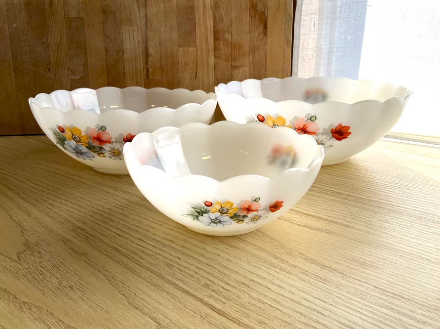 Set of 3 Arcopal scalloped tempered milk glass salad bowls with small flowers on the outside. One large, one medium, one small on a wood cutting board background