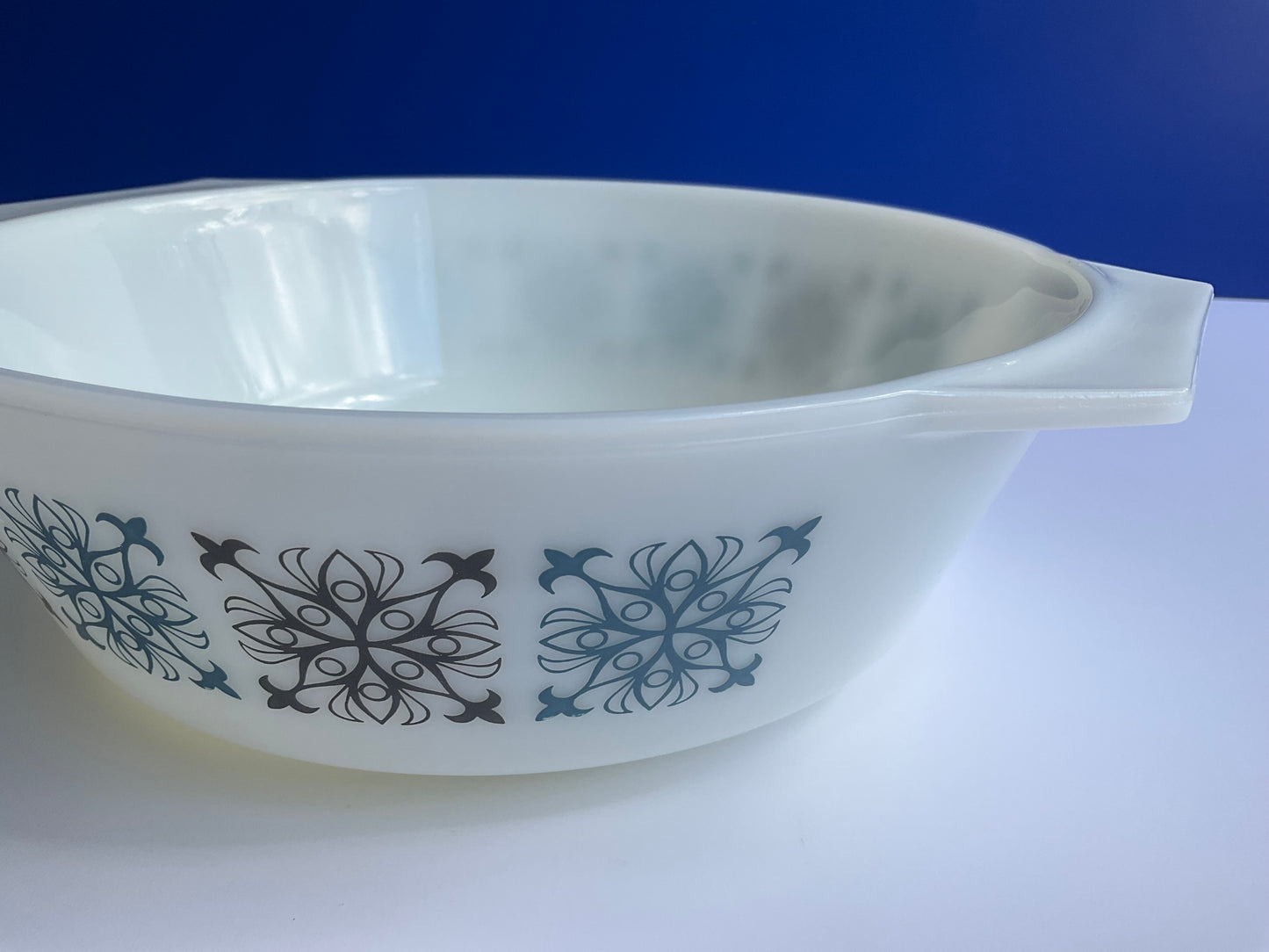 Side view of Pyrex JAJ tempered milk glass oven casserole with Chelsea blue and black geometric pattern without lid on a blue and white background 