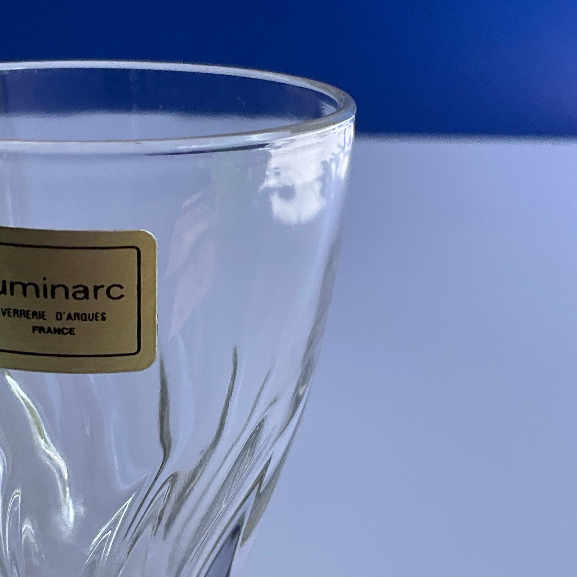 Close up view of Luminarc stemmed swirly tempered vine glass with gold label on a white background