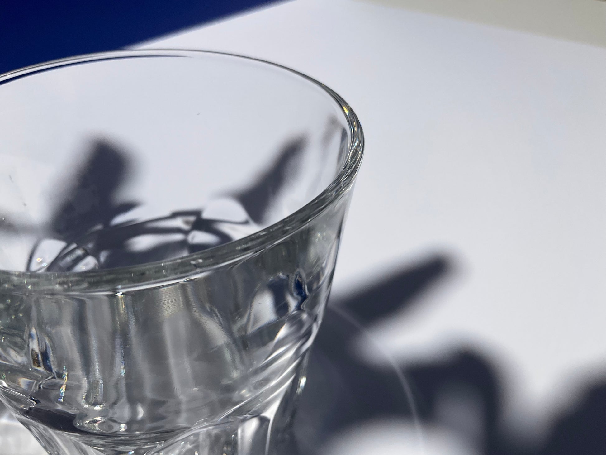 Close up view of the rim of a clear tempered glass Arc France tumbler on a bleu and white background