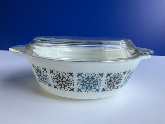 Front view of a Pyrex JAJ tempered milk glass oven casserole with Chelsea blue and black geometric pattern and a clear glass lid on a blue and white background 