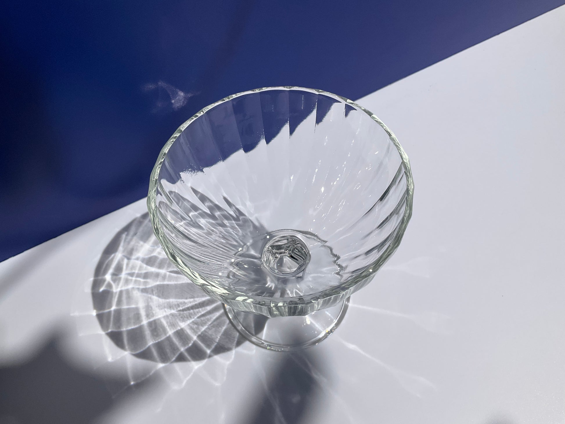 Clear tempered  glass Arc France stemmed dessert cup on blue and white background view rom above