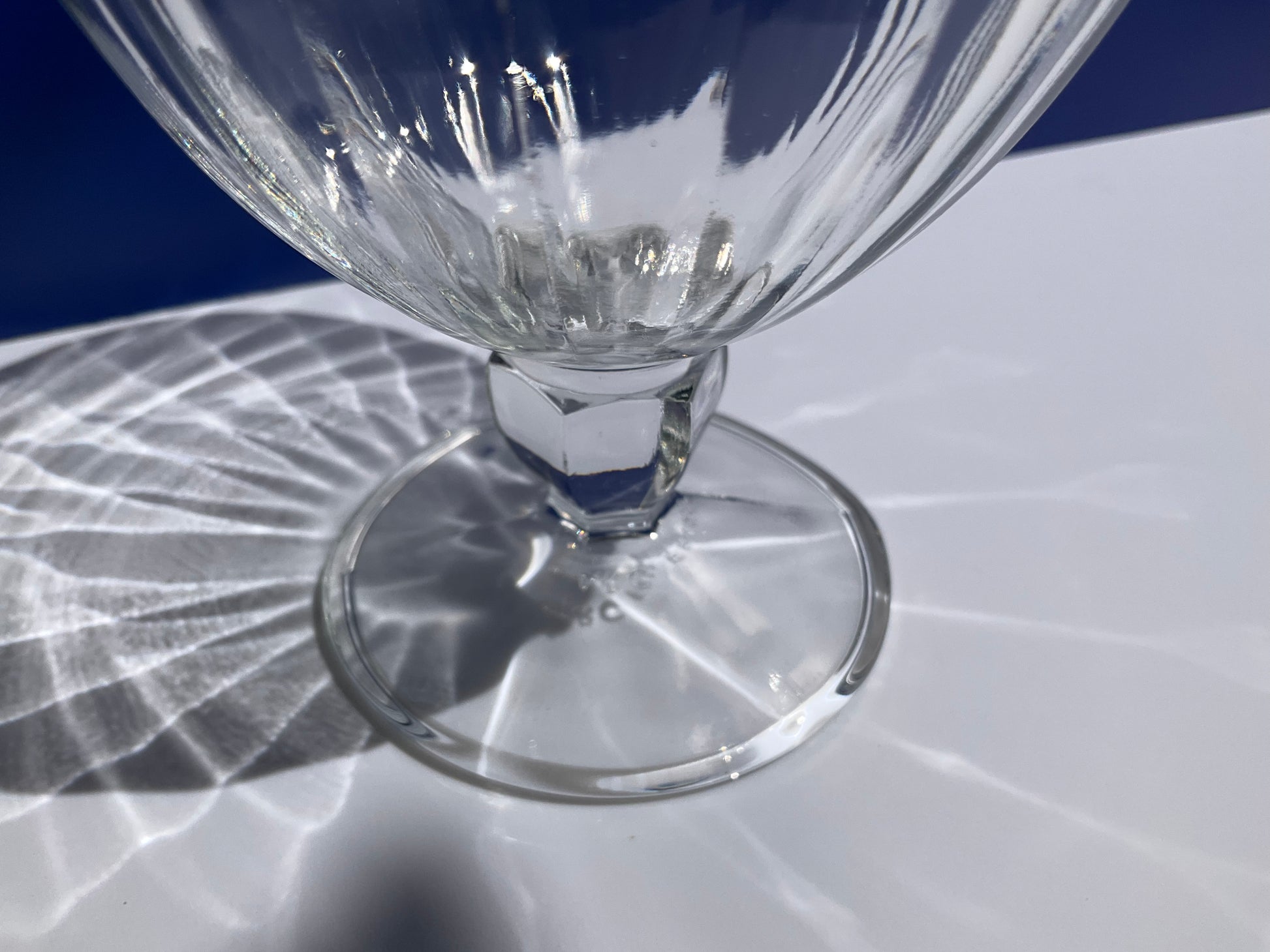 Close up of base of Arc France stemmed clear tempered glass dessert cup on blue and white background