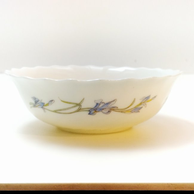 Centered front view of a white tempered milk glass small bowl with blue iris pattern by Arcopal France on a white background