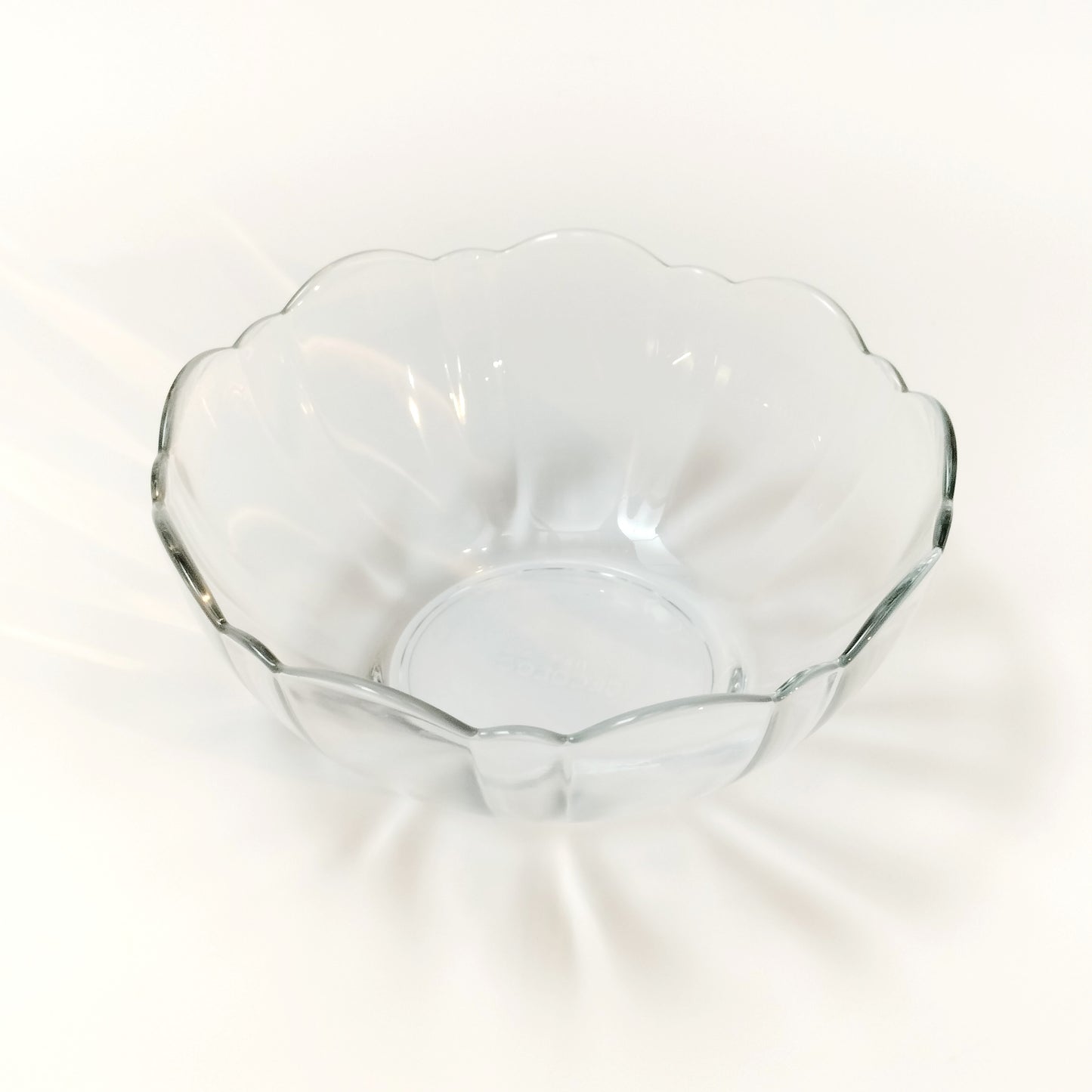 Top view of scalloped clear tempered glass bowl by Arcoroc on white background