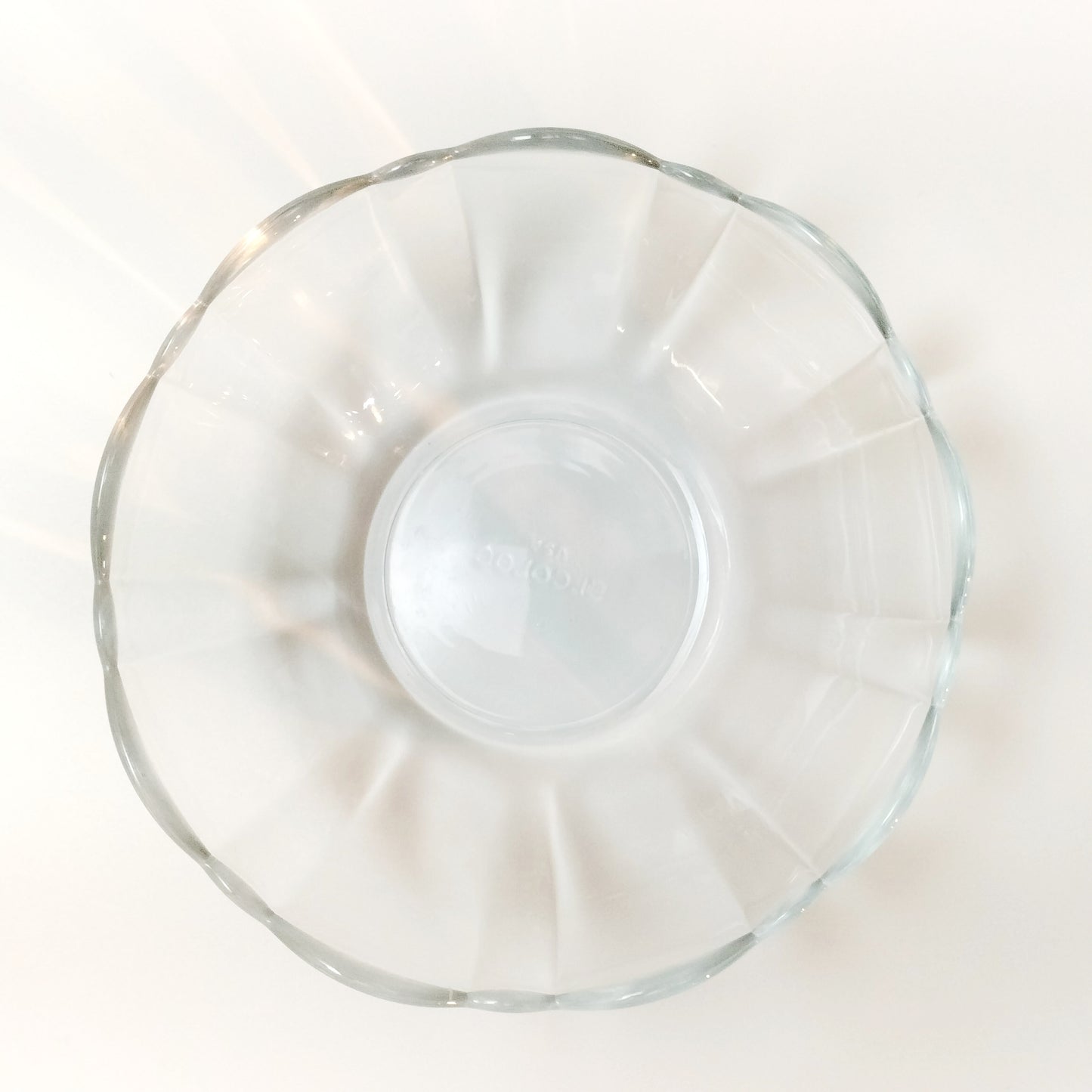 Top view of scalloped clear tempered glass bowl by Arcoroc on white background