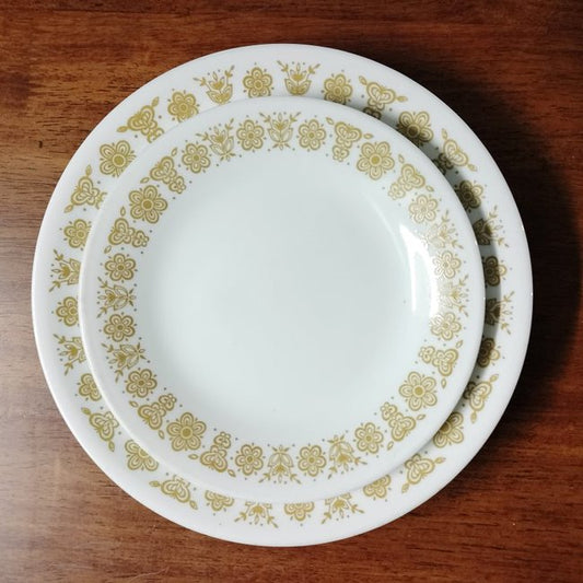 White tempered milk glass dinner plate set with yellow butterfly design by Corelle on a wood background