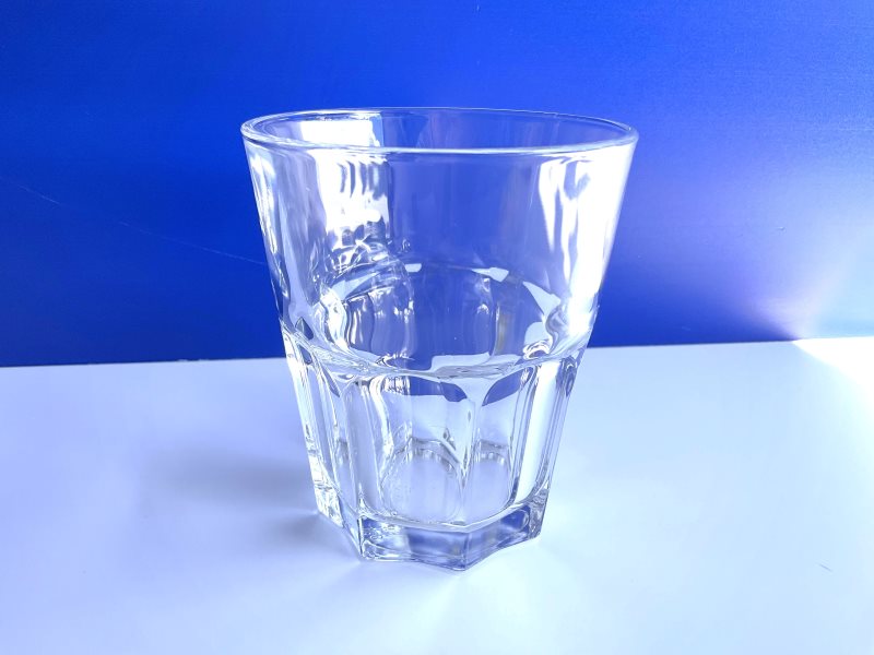 Front view of a clear tempered glass Arc France tumbler on a bleu and white background